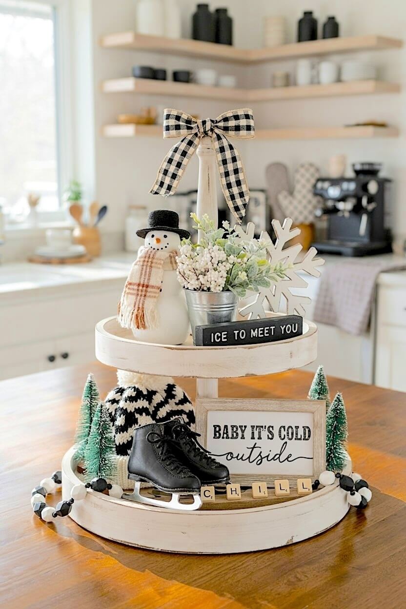 Miniature black ice skates rest near a knitted beanie and a smiling snowman under a black and white gingham bow for playful snowy season tray inspirations.