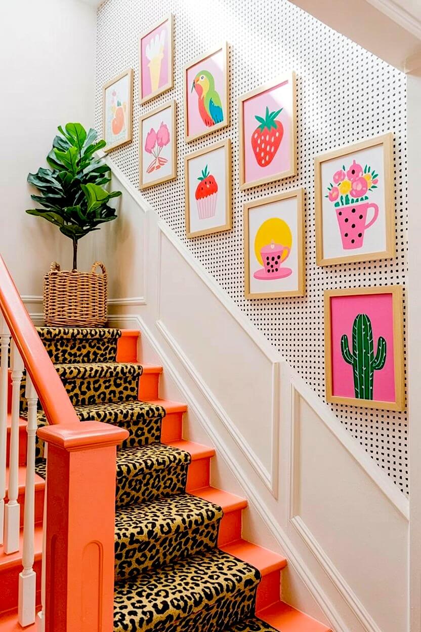Cheerful illustrations of strawberries, a parrot, and a cactus in light wood frames mounted on black and white polka dot wallpaper for fun stairway decor.